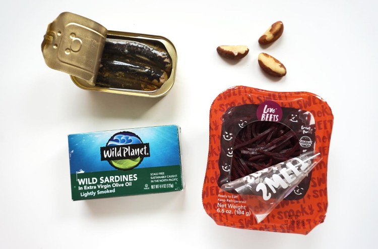 open can of sardines above a wild plant wild sardines box next to 3 brazil nuts and a container of love beets shredded beets