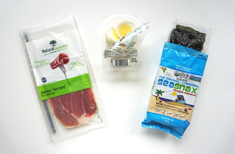 packet of prosciutto beside hard boiled eggs beside a container of sea snax original seaweed snacks