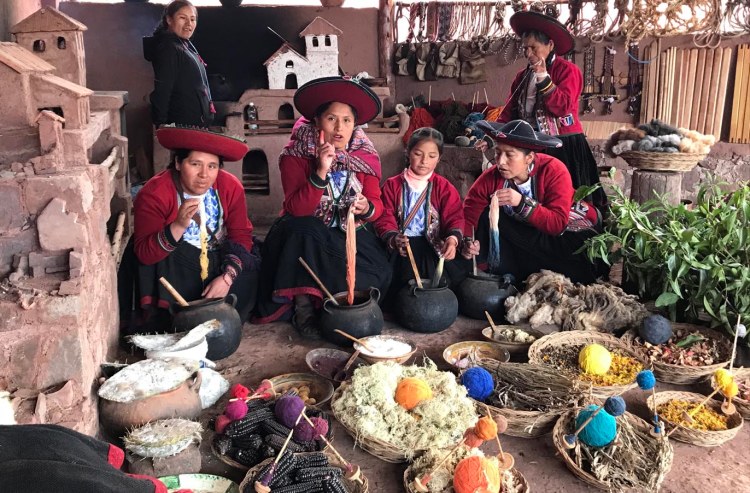 four peruvian women in traditional peruvian costume dying yarn