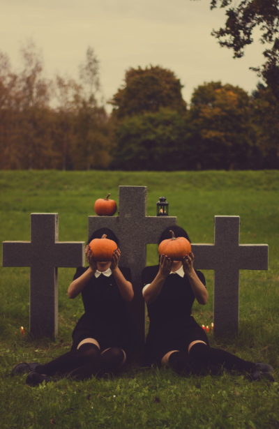 spooky girls with pumpkins in cemetary